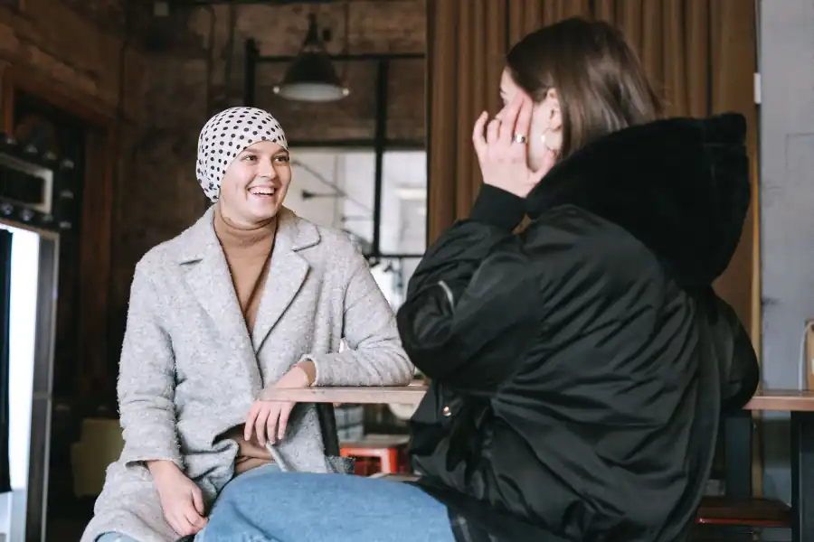 Duas mulheres sorrindo, sentadas à mesa de um café